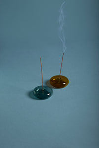 Lit DEEPS Incense sticks sit on blue and orange blown-glass holders